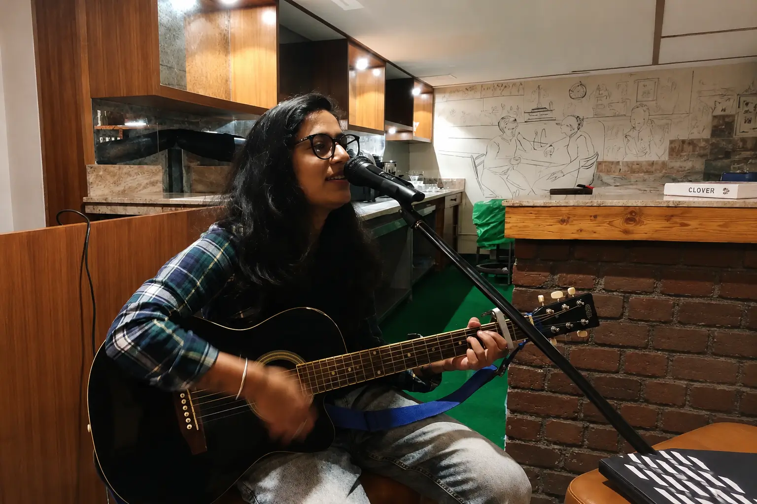 Female singer performing live with acoustic guitar at indoor café event in Solan for weddings and private celebrations